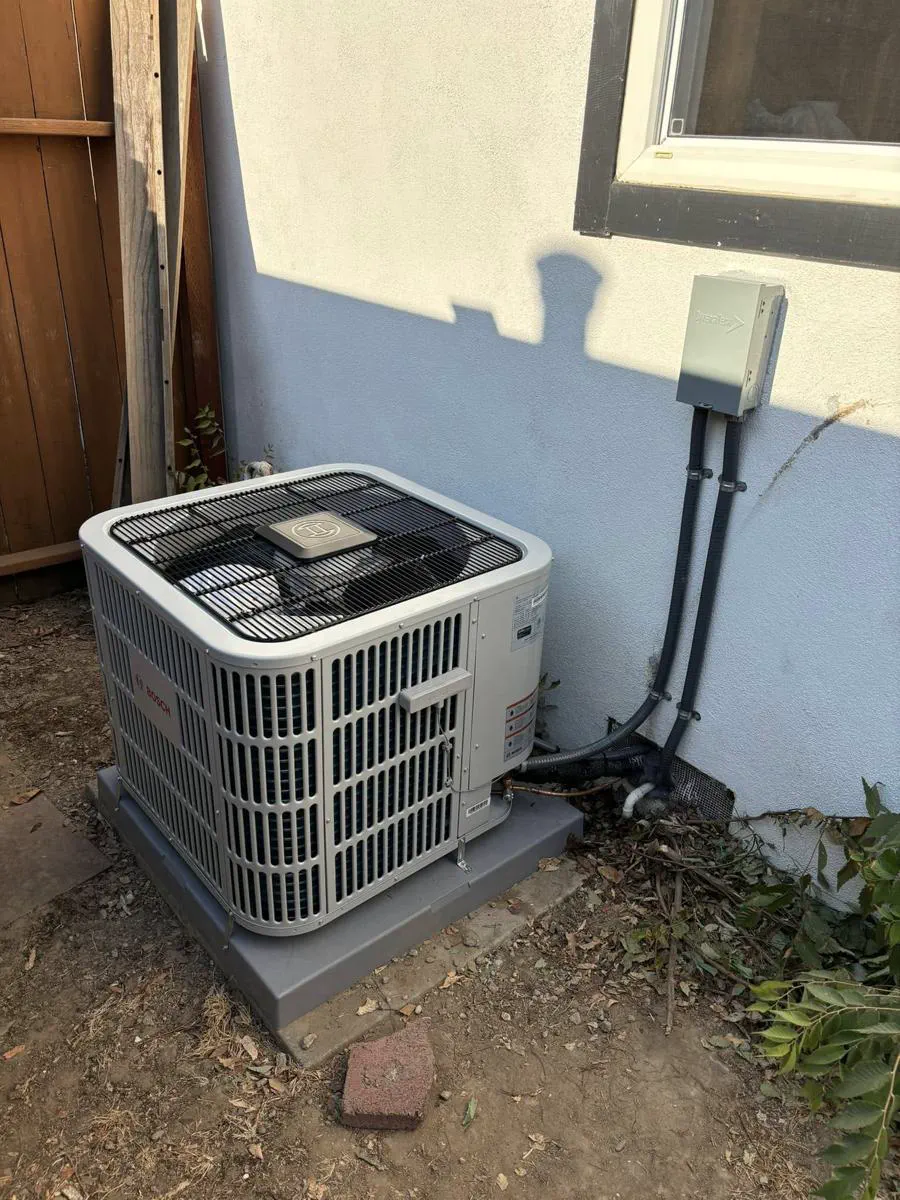 A new Bosch condenser installed against a white stucco wall