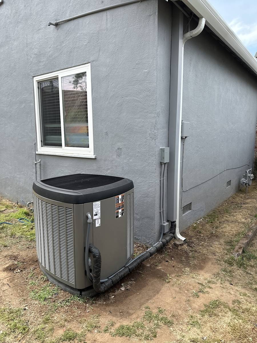 A gray condenser unit installed beside a window