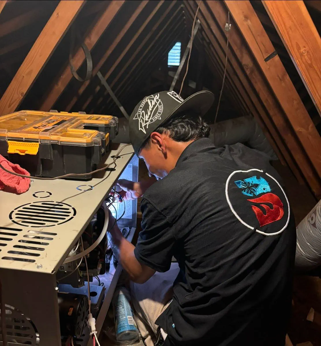 A Barraza technician working on a furnace in an attic