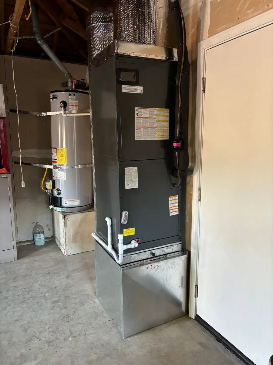 A new furnace and air handler installed in a garage next to a water heater