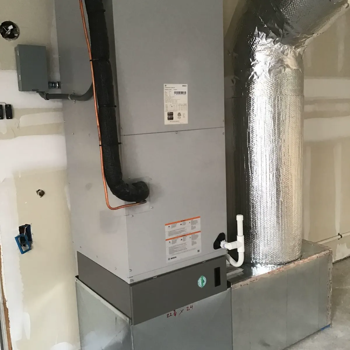 An air handler connected to new insulated ductwork in a garage